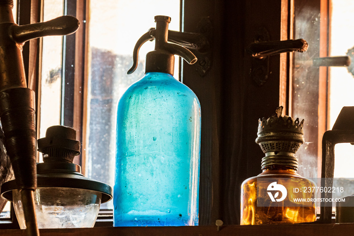 Siphon for soda water. A vintage blue glass soda siphon stands on a shelf surrounded by ancient artifacts. Colorful details. Retro.