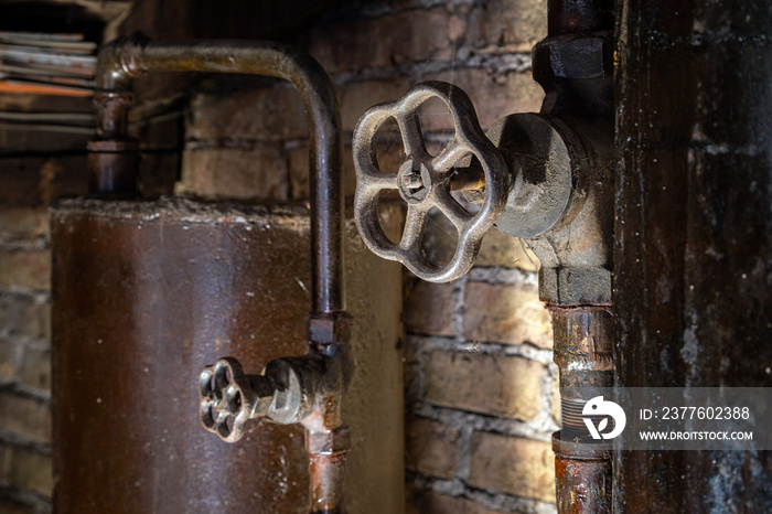 Rusty boiler room pipes. Old metal boiler generating heating and delivering it to home through pipeline. Hot water or gas is being delivered with this system