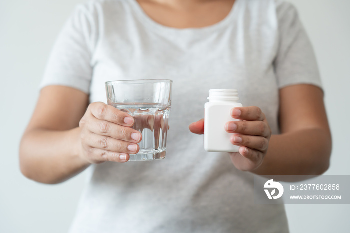 Asian woman close up ready to take supplement pill holding a glass of water. Sick person need medicine and water for good health.