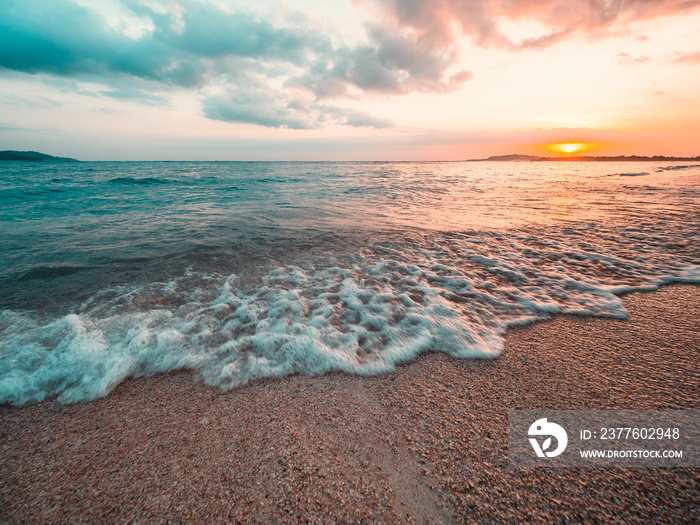 Ocean sunset, slow shutter, waves washing in over the sand. Strong sunset colors and clouds over the horizon