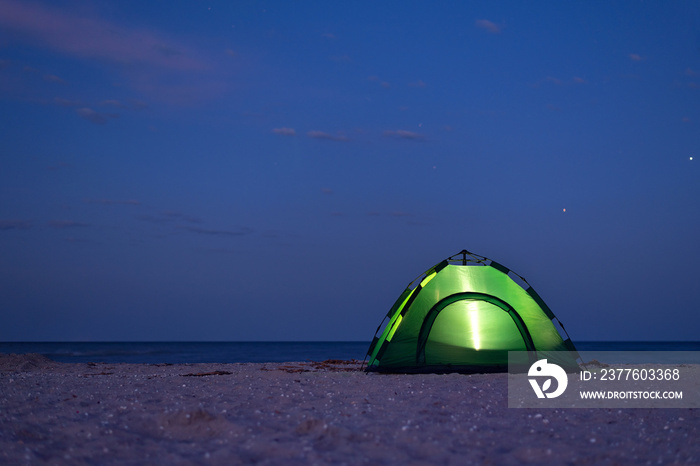 Tent is lit up at night. Tent under the starry by the sea shore