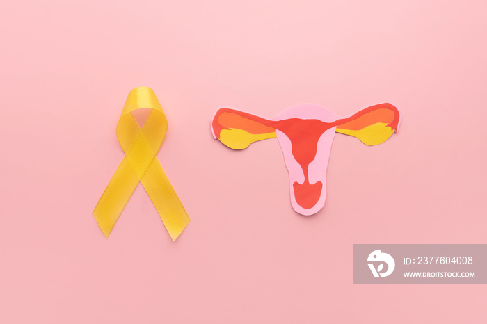 Yellow ribbon awareness with uterus shape made frome paper on pink background. Symbol of  National Endometriosis awareness month of March. Female reproductive health concept.