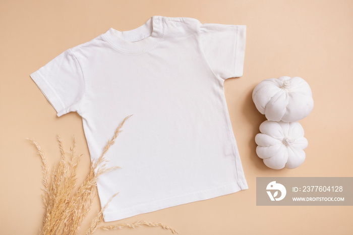 White baby t-shirt top view. Mock-up for logo, text or design on beige background. Flat lay child clothes