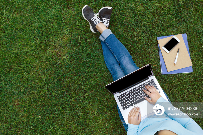 Top view of female student sitting in park with laptop