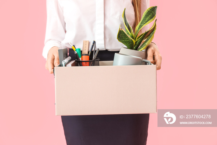 Fired young woman holding box with her stuff on pink background, closeup