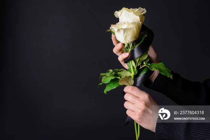 Mourning woman with flowers and black ribbon on dark background