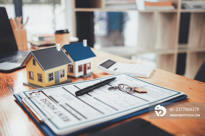 Real estate sales documents and model homes are placed on tables inside real estate sales offices to prepare prospective buyers to sign real estate sales contracts with dealers.