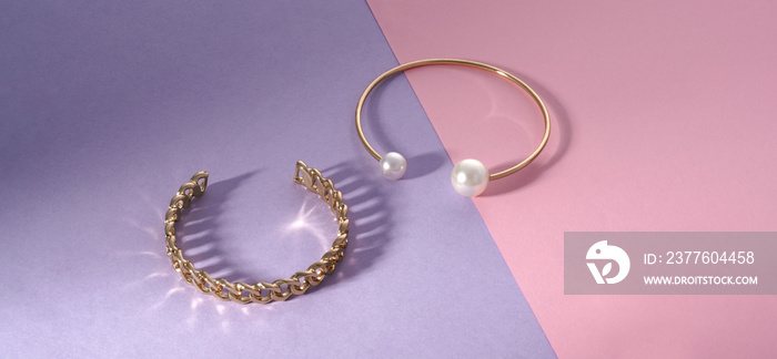 Panorama of Chain shape and golden with pearls bracelets on pink and purple paper