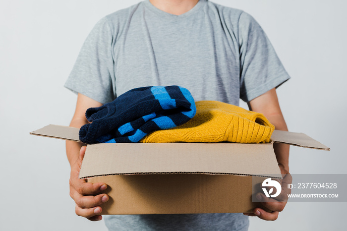 man holding a crate of second-hand clothes unused clothes