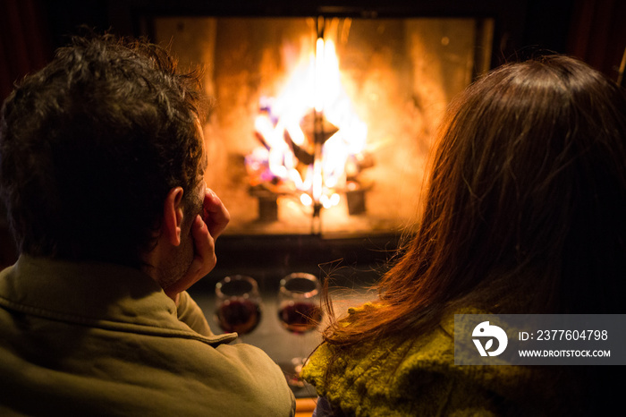 Couple sitting at warm fireplace with wine