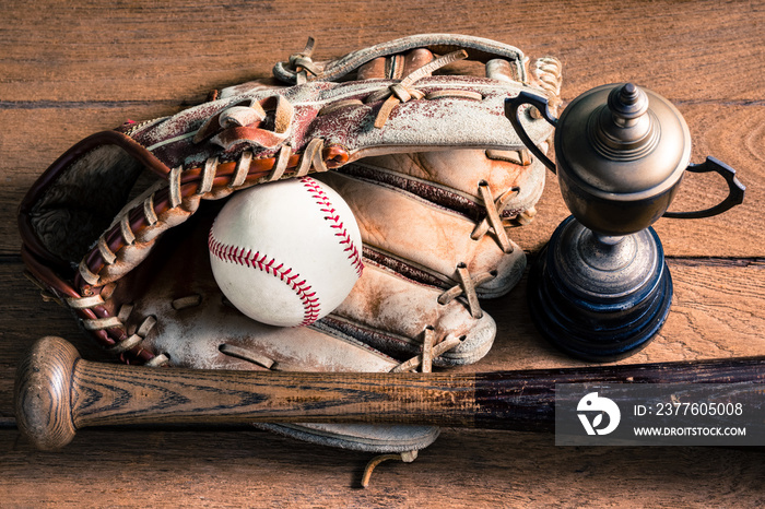 worn out baseball equipment ( ball, baseball bat and glove ) with old trophy on old wood