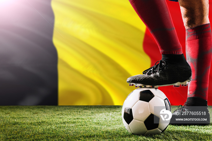 Close up legs of Belgium football team player in red socks, shoes on soccer ball at the free kick or penalty spot playing on grass.