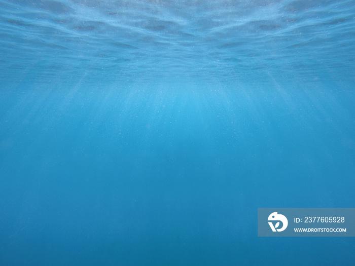 Blue water surface and ripples with rays of light under water. Ocean underwater background. Sea water splash texture. Horizontal wallpaper. 3d render effect. Nature and fresh concept.