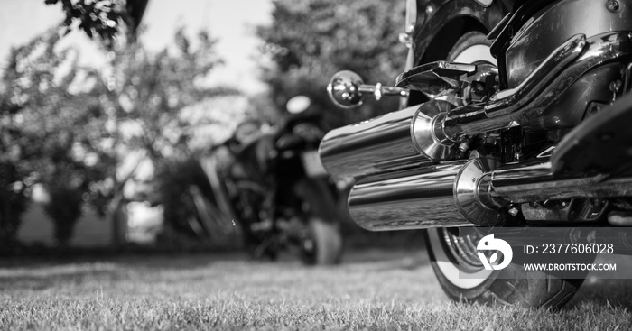 Chromed motorcycle exhaust,  photographed outdoors. Black and white photo.