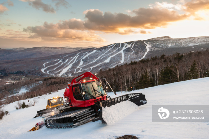 A fleet of snowcats grooming Spruce Peak at dusk with Mt. Mansfield in the background, Stowe, Vermont, USA