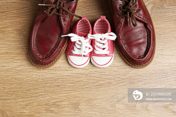 Big and small shoes on wooden background