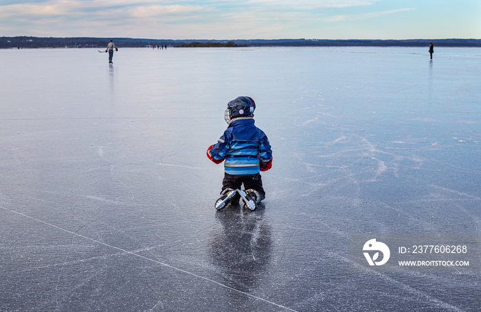 Boy ice skating on icy lake