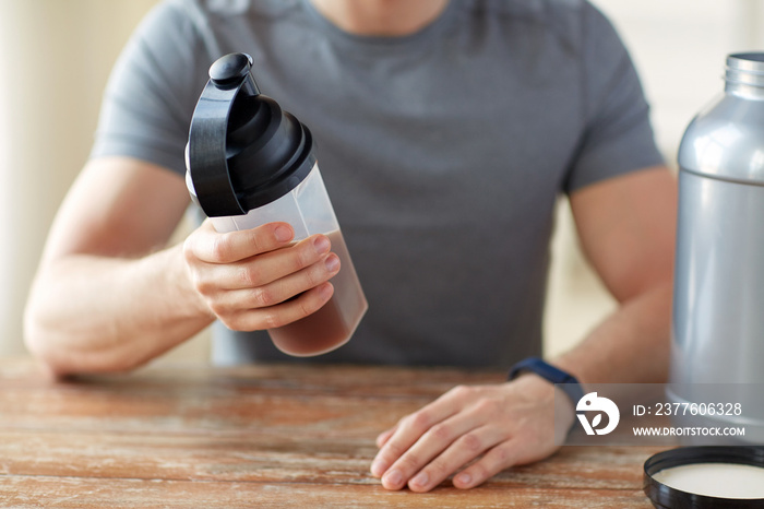 close up of man with protein shake bottle and jar