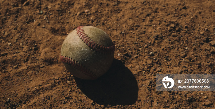 Old used baseball ball in game field dirt with copy space on background for summer sport.