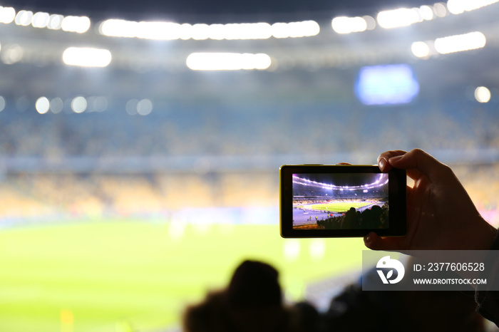 Fan taking video of football game at stadium