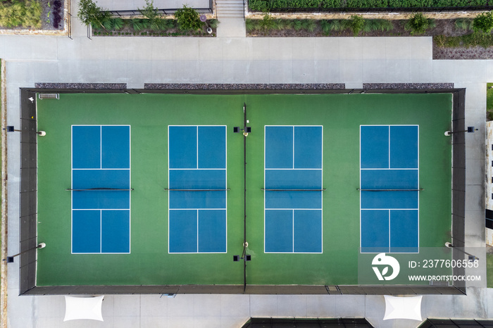 View from above, aerial view of four blue public, empty tennis courts, tennis playgrounds in the summertime outdoor.