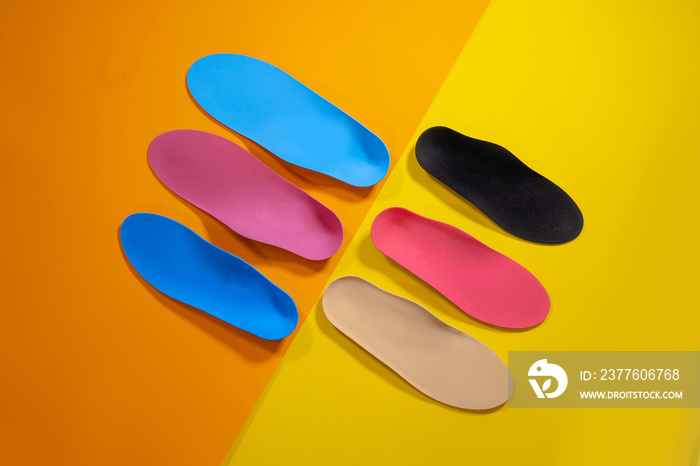 Orthopedic insoles for shoes on a colour background. Foot care