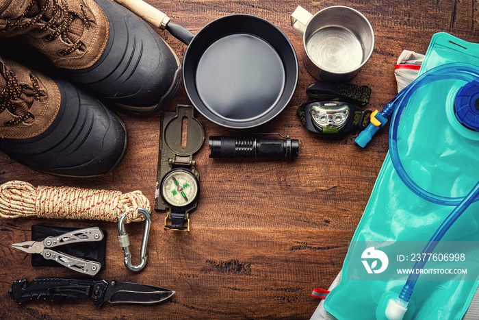 Outdoor travel equipment planning for a mountain trekking camping trip on wooden background. Top view - vintage film grain filter effect styles