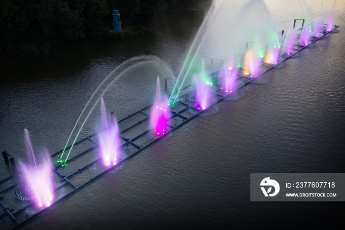 Colored fountain on the river at night.