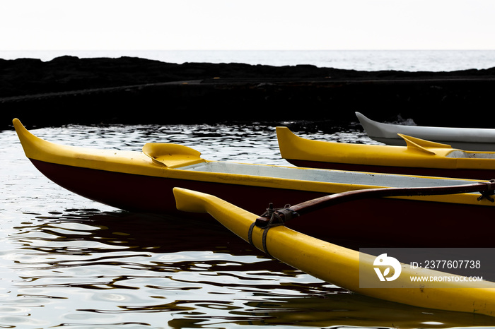 Prow Of Three Hawaiian Canoes Sitting In Water