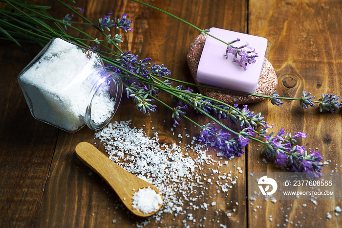 Spa massage setting with lavender flowers, soap and cosmetic salt on wooden background.