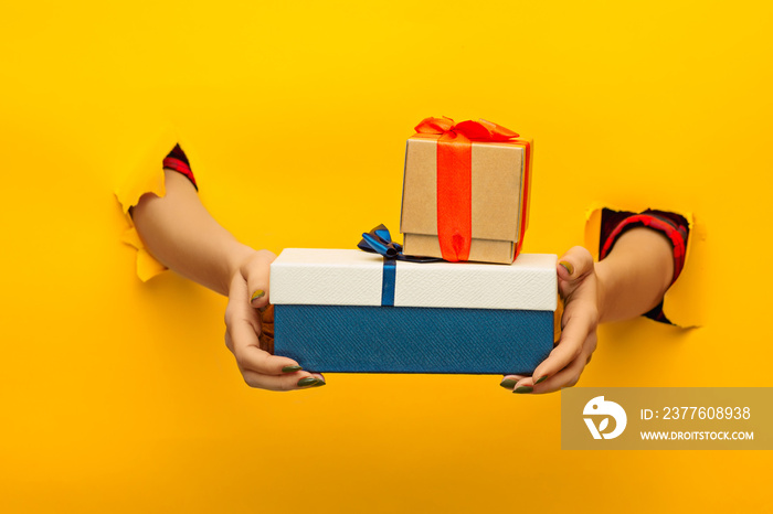 close-up of female hand holding a present through a torn paper, isolated