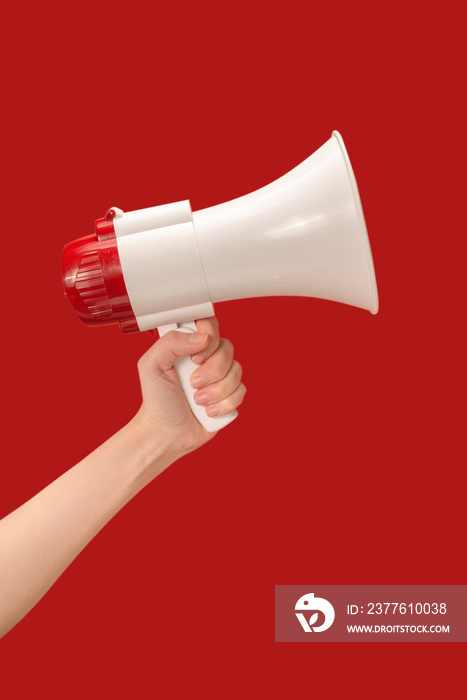 Megaphone in woman hands on a red background.