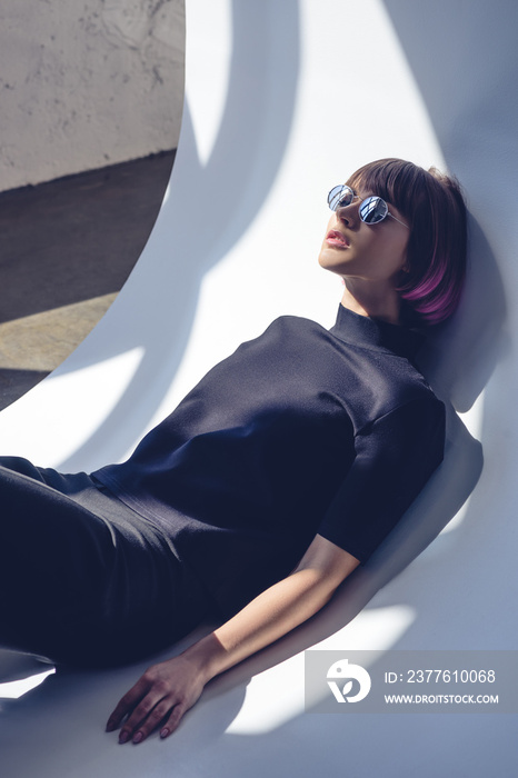 stylish girl lying in black clothes and sunglasses