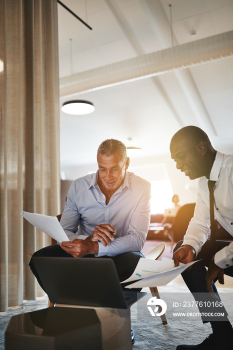 Two smiling businessmen working together in a modern office