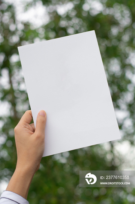 Woman holding paper blank of drawing paper paper with natural background.