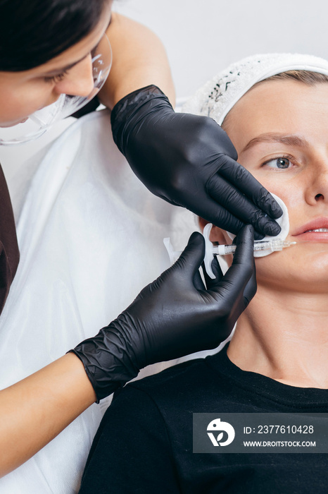 Doctor in gloves  giving woman injections in lips