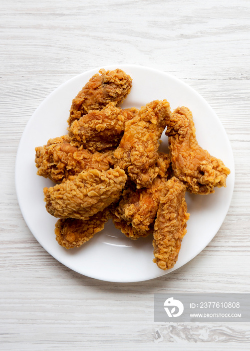 Top view, chicken wings on a round white plate over white wooden surface, top view. Flat lay, overhead.