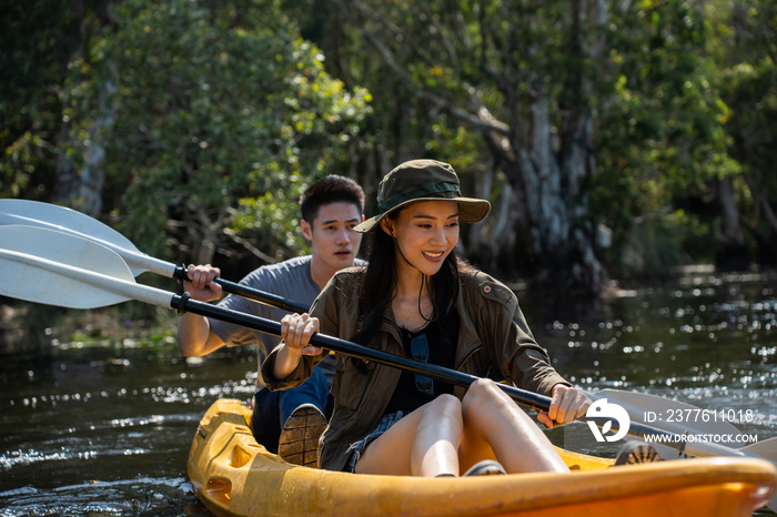 Asian attractive romantic young couple rowing kayak in a forest lake.