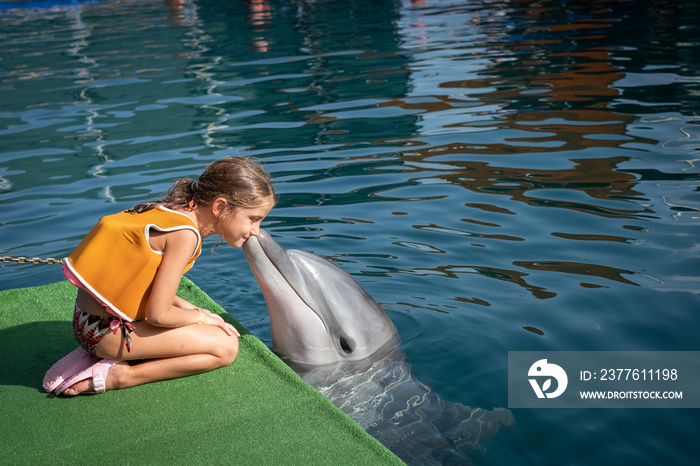 a kid girl playing with a dolphin