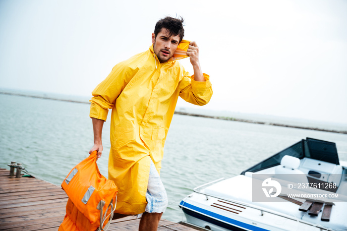 Sailor man in yellow cloak walking at the sea pier