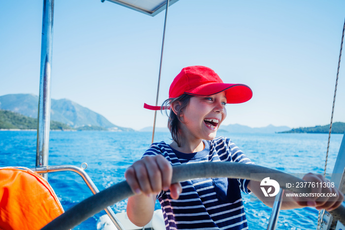 Little boy captain on board of sailing yacht on summer cruise. Travel adventure, yachting with child on family vacation.