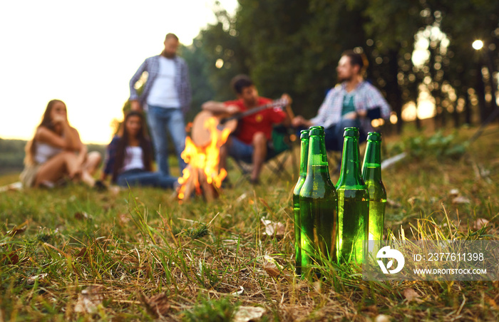 Beer bottles on the background of friends by the bonfire on a picnic.