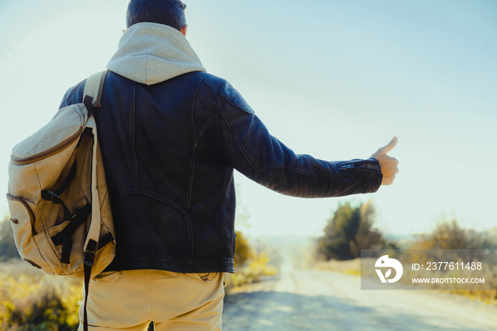 Man is hitchhiking on background of road