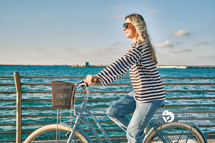 Carefree woman with bike riding on beach having fun, on the seaside