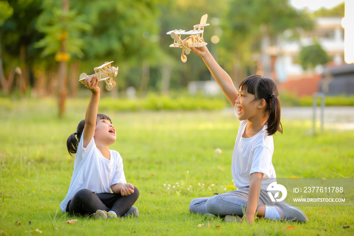 Two cute little girl asia playing toy airplane on nature in the park. Little dreams of flying limitless imagination .Which increases the development and enhances learning skills.