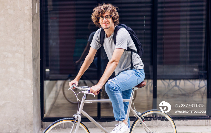 Portrait of casual hipster handsome businessman with backpack looking at camera while commuting riding bicycle on the street city way go to work.business travel transport bike concept