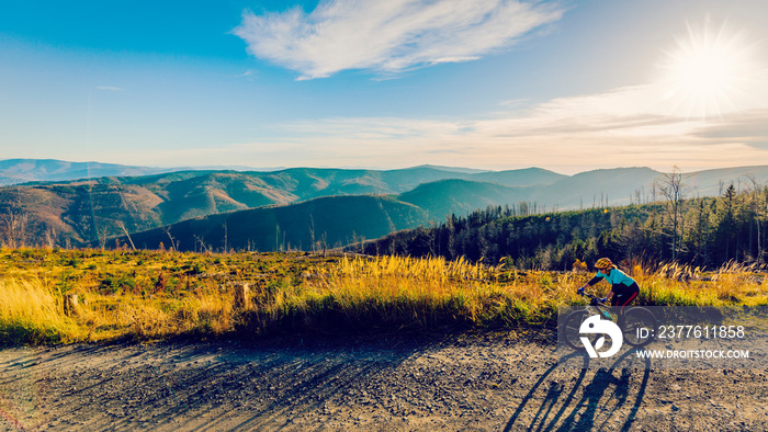 Cycling woman riding on bike in autumn mountains forest landscape. Woman cycling MTB flow trail track. Outdoor sport activity.