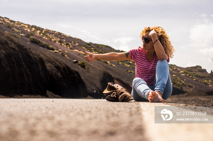 middle age woman people do hitch hiking sitting on the road with broken shoes and barefoot trekking lifestyle. travel concept for lady and freedom life over the world - vagabond and traveler style