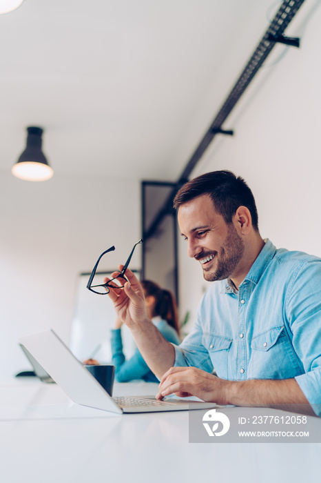 Businessman using laptop and smiling in the office