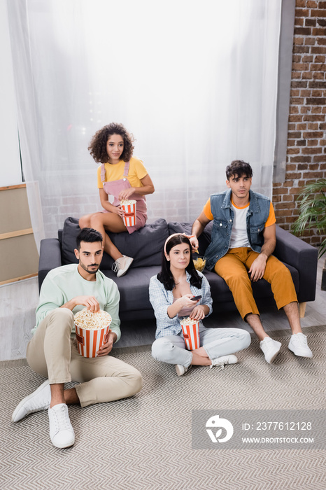 high angle view of hispanic friends with popcorn buckets watching tv at home